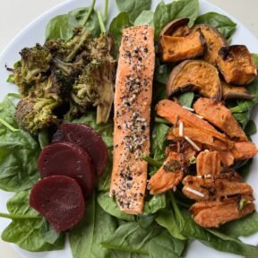 Everything Bagel Crusted Salmon on spinach salad with roasted vegetables
